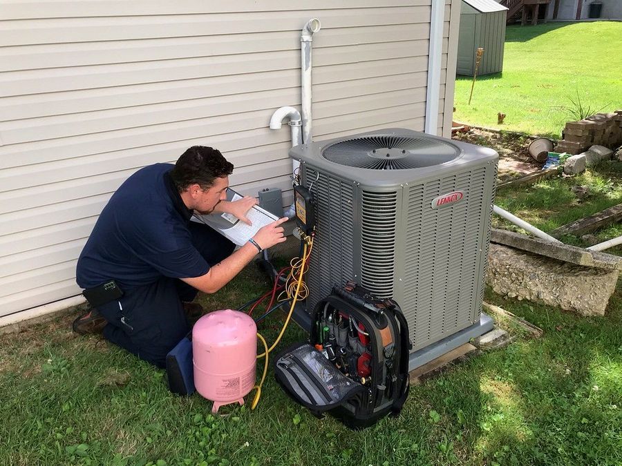 Technician checking refrigerant gas pressure on an AC condenser unit